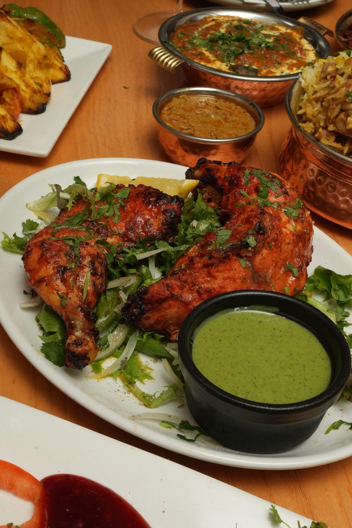 Chicken tandoori with charred edges, served with wedges of lemon
