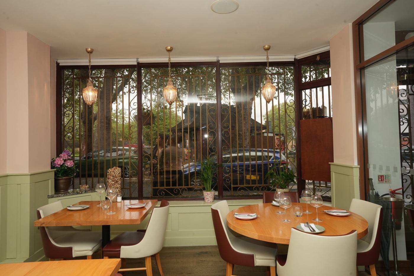 Tables set by the bay window in daylight at Aara